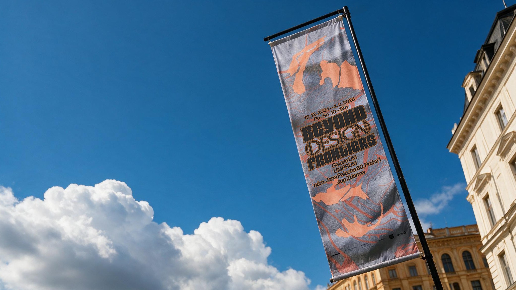A 'Beyond Design Frontiers' flag banner hanging outside a building against a blue sky