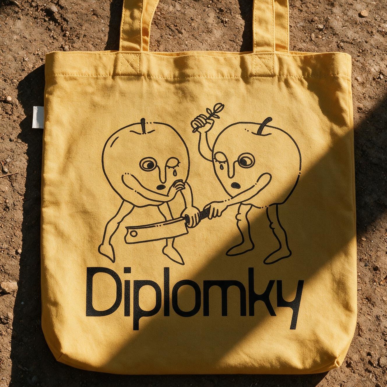 A yellow tote bag printed with the Diplomky logo and character illustration