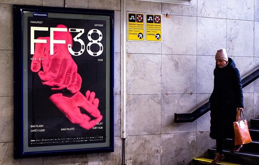 An FF38 poster lit up at night on a concrete wall beside a pedestrian underpass