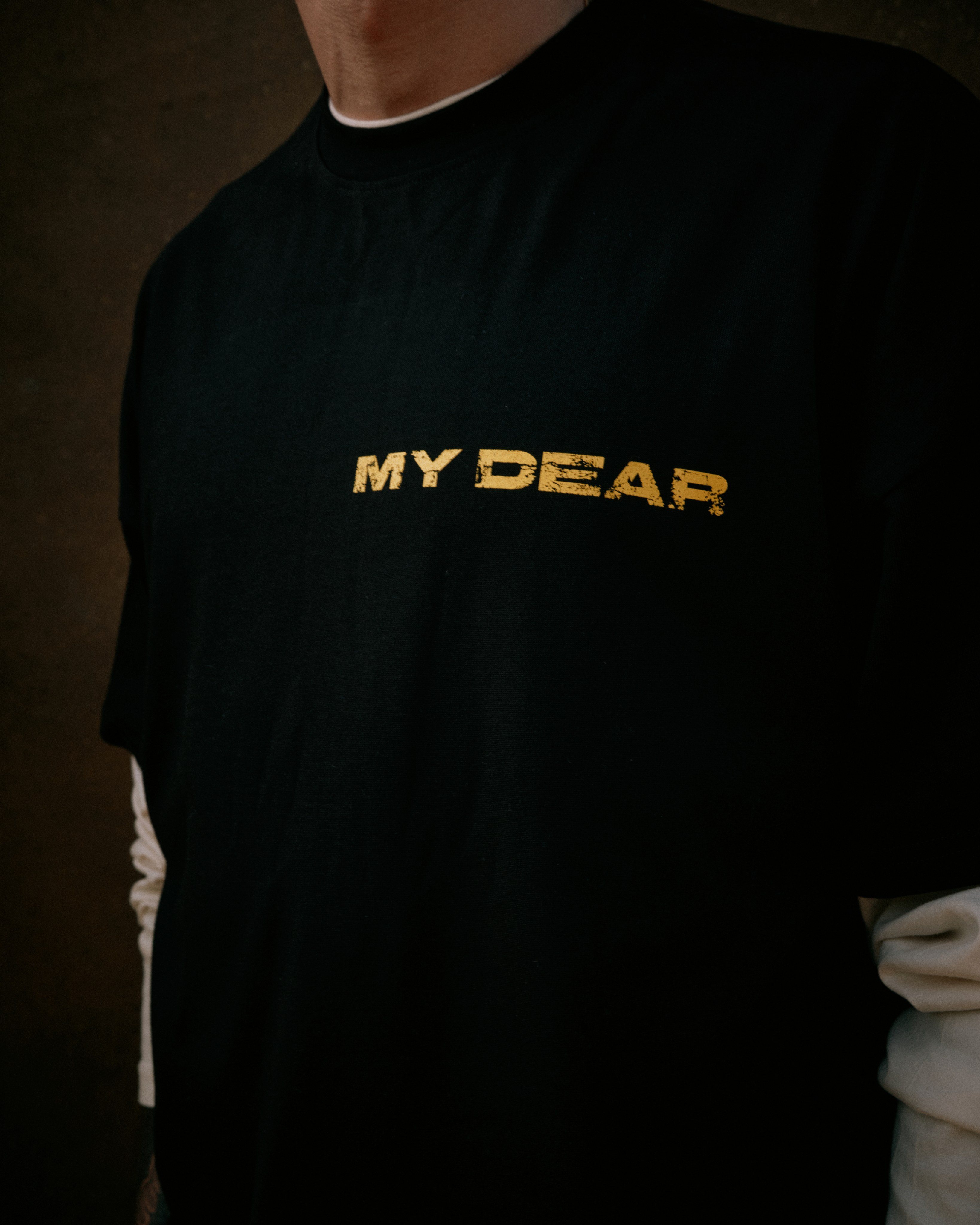 Close-up of a black t-shirt with the 'My Dear' logo printed in gold